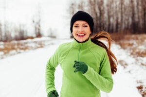 Bieganie zimą – młoda kobieta na zimowym treningu w lesie
